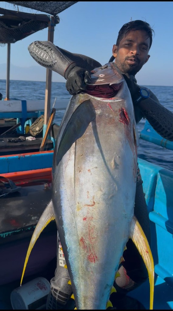 Waqar Khan holding a yellowfin tuna at sea